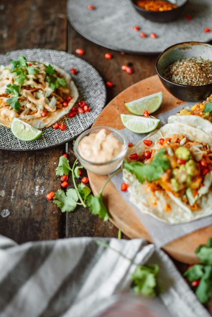 A top view of assorted Mexican tacos with lime, cilantro, and fresh toppings.